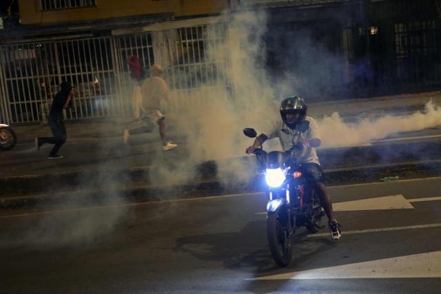 Demonstrators run from tear gas as they protest against the preliminary results of the presidential runoff election in Cali, Colombia, on June 21, 2026. A flamboyant US-backed lawyer who has never held public office narrowly won Colombia's presidential runoff Sunday, swinging the country hard to the right on a promise to wage war against drug-running guerrilla groups. With more than 99 percent of polling centers reporting, Abelardo de la Espriella had 49.67 percent of the vote, an unassailable lead over his rival, left-wing Senator Ivan Cepeda who trailed at 48.69 percent, according to official results. (Photo by JOAQUIN SARMIENTO / AFP)