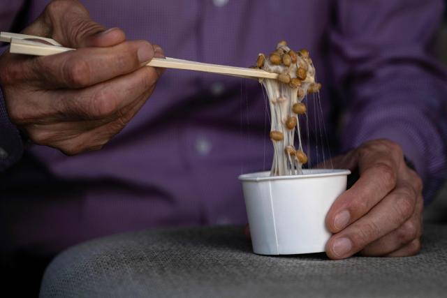This photo taken on May 15, 2026 shows Yoshihiro Noro, owner of the Kamakurayama Natto production facility, mixing natto at his store in Kamakura, Kanagawa prefecture. The highly nutritious beans inoculated with beneficial bacteria remain a traditional Japanese breakfast staple, but their pungent aroma, viscous texture and yeasty taste divide even their homeland. Recent years have seen natto join a series of fermented foods, from kimchi to kombucha, that have surged in popularity worldwide as Americans in particular seek better digestive health following the Covid-19 pandemic. (Photo by Andrew CABALLERO-REYNOLDS / AFP) / To go with AFP story Japan-food-health-natto-lifestyle,FEATURE by Tomohiro Osaki and Sarah Lai