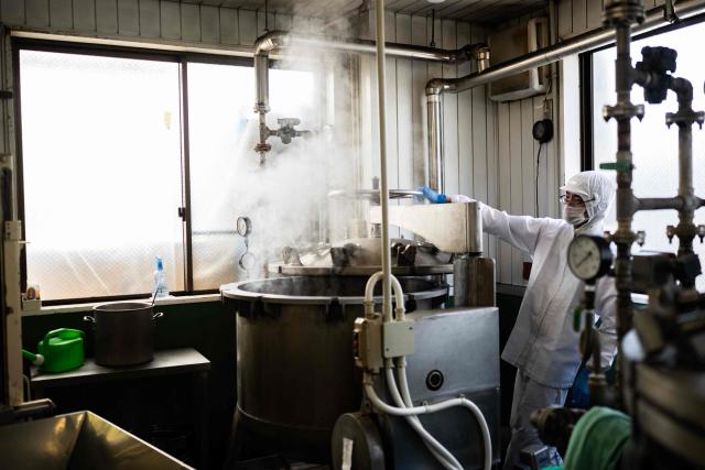 This photo taken on May 15, 2026 shows an employee opening a pressure cooker with soybeans at the Kamakurayama Natto production facility in Kamakura, Kanagawa prefecture. The highly nutritious beans inoculated with beneficial bacteria remain a traditional Japanese breakfast staple, but their pungent aroma, viscous texture and yeasty taste divide even their homeland. Recent years have seen natto join a series of fermented foods, from kimchi to kombucha, that have surged in popularity worldwide as Americans in particular seek better digestive health following the Covid-19 pandemic. (Photo by Andrew CABALLERO-REYNOLDS / AFP) / To go with AFP story Japan-food-health-natto-lifestyle,FEATURE by Tomohiro Osaki and Sarah Lai