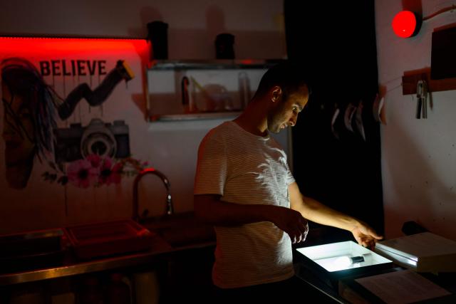 Syrian photographer, educator and co-founder of the project Serbest Salih checks darkroom equipment during a workshop held as part of Fotohane Darkroom project in Mardin, southeastern Turkey, on June 13, 2026. In a dimly lit room illuminated by a pair of red lamps, eight-year-old Zeynep waits to see the photographs she has taken, now trapped as shadows and silhouettes on a roll of film. Originally from the southeastern province of Mardin, Zeynep is among eight children taking part in a two-month analog photography workshop for local and migrant youth near Turkey's borders with Iraq and Syria. The project, called Fotohane Darkroom, started in Mardin in 2024, by Kilic and Syrian photographer and educator Serbest Salih. In Turkish, Arabic, Kurdish and Persian, Fotohane means "house of photo", a name chosen by the children. (Photo by Yasin AKGUL / AFP)