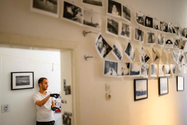 Syrian photographer, educator and co-founder of the project Serbest Salih speaks to children during a workshop held as part of Fotohane Darkroom project in Mardin, southeastern Turkey, on June 13, 2026. In a dimly lit room illuminated by a pair of red lamps, eight-year-old Zeynep waits to see the photographs she has taken, now trapped as shadows and silhouettes on a roll of film. Originally from the southeastern province of Mardin, Zeynep is among eight children taking part in a two-month analog photography workshop for local and migrant youth near Turkey's borders with Iraq and Syria. The project, called Fotohane Darkroom, started in Mardin in 2024, by Kilic and Syrian photographer and educator Serbest Salih. In Turkish, Arabic, Kurdish and Persian, Fotohane means "house of photo", a name chosen by the children. (Photo by Yasin AKGUL / AFP)