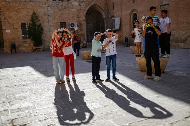 A group of children take pictures in the streets with their film cameras during a workshop held as part of Fotohane Darkroom project in Mardin, southeastern Turkey, on June 14, 2026. In a dimly lit room illuminated by a pair of red lamps, eight-year-old Zeynep waits to see the photographs she has taken, now trapped as shadows and silhouettes on a roll of film. Originally from the southeastern province of Mardin, Zeynep is among eight children taking part in a two-month analog photography workshop for local and migrant youth near Turkey's borders with Iraq and Syria. The project, called Fotohane Darkroom, started in Mardin in 2024, by Kilic and Syrian photographer and educator Serbest Salih. In Turkish, Arabic, Kurdish and Persian, Fotohane means "house of photo", a name chosen by the children. (Photo by Yasin AKGUL / AFP)