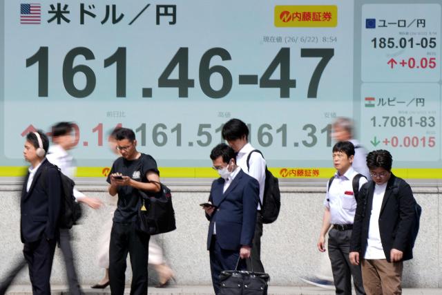 Pedestrians stand in front of electronic boards displaying the foreign exchange rate of the Japanese yen against the US dollar (L) and other currencies (R), along a street in Tokyo on June 22, 2026. (Photo by AFP)