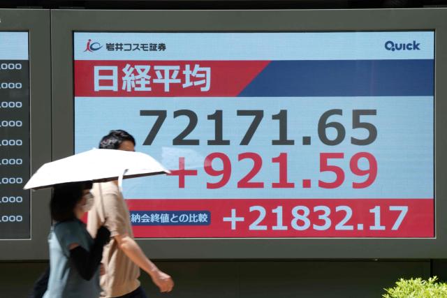Pedestrians walk past an electronic quotation board displaying the Nikkei Stock Average on the Tokyo Stock Exchange in Tokyo on June 22, 2026. (Photo by AFP)