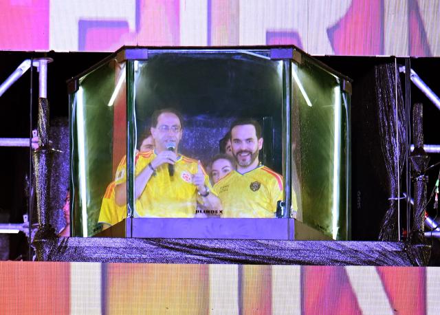 Colombia's presidential candidate for the Defensores de la Patria movement, Abelardo de la Espriella (R) and running mate Jose Manuel Restrepo speak to supporters from behind a bullet-proof glass following the preliminary results of the presidential runoff election at the Ventana al Mundo monument in Barranquilla, Colombia, on June 21, 2026. A flamboyant US-backed lawyer who has never held public office narrowly won Colombia's presidential runoff on June 21, swinging the country hard to the right on a promise to wage war against drug-running guerrilla groups. With just a handful of polling centers left to report, Abelardo de la Espriella had 49.65 percent of the vote -- an unassailable lead over left-wing Senator Ivan Cepeda who trailed on 48.70 percent. (Photo by Juan BARRETO / AFP)