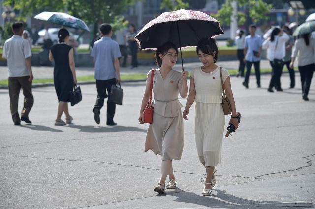 Women walk under an umbrella along a street near the railway station in Pyongyang on June 22, 2026. (Photo by KIM Won Jin / AFP)