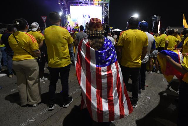 A supporter of Colombia's presidential candidate for the Defensores de la Patria movement, Abelardo de la Espriella wrapped on an US flag waits for the preliminary results of the presidential runoff election at the Ventana al Mundo monument in Barranquilla, Colombia, on June 21, 2026. A flamboyant US-backed lawyer who has never held public office narrowly won Colombia's presidential runoff on June 21, swinging the country hard to the right on a promise to wage war against drug-running guerrilla groups. With just a handful of polling centers left to report, Abelardo de la Espriella had 49.65 percent of the vote -- an unassailable lead over left-wing Senator Ivan Cepeda who trailed on 48.70 percent. (Photo by Jaime SALDARRIAGA / AFP)