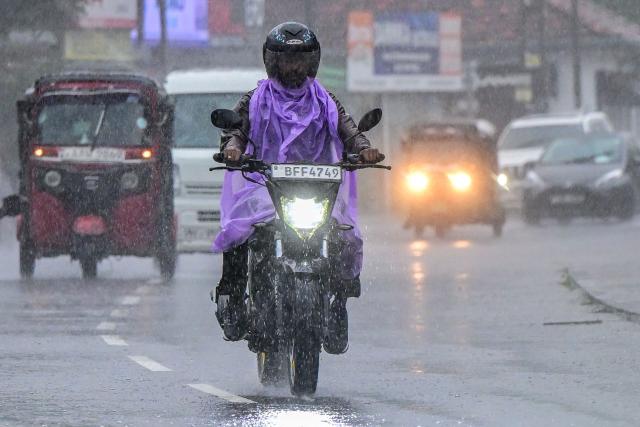 A motorcyclist rides along a street during a spell of heavy rain in Colombo on June 22, 2026. (Photo by Ishara S. KODIKARA / AFP)