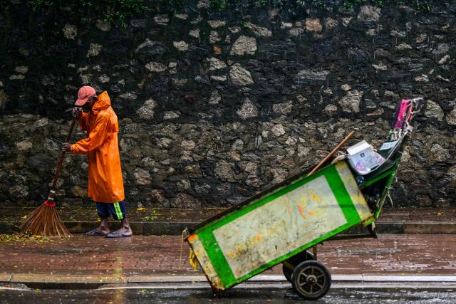 A municipal worker sweeps a road during a spell of heavy rain in Colombo on June 22, 2026. (Photo by Ishara S. KODIKARA / AFP)