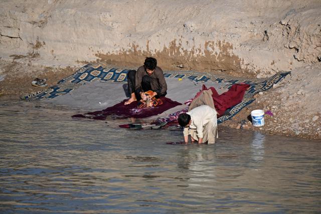 A man washes carpets along a canal at Loy Viala village in the 9th district of Afghanistan's Kandahar on June 21, 2026. (Photo by Sanaullah SEIAM / AFP)