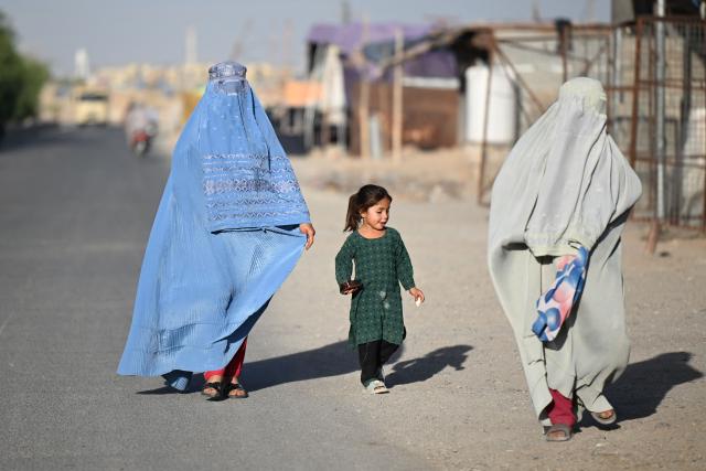 TOPSHOT - Afghan burqa-clad women along with a girl walk along a street in Loy Viala village in Afghanistan's Kandahar on June 21, 2026. (Photo by Sanaullah SEIAM / AFP)