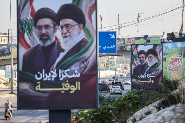 Cars and motorbikes drive past billboards showing Iran’s new Supreme Leader Ayatollah Mojtaba Khamenei (L) and his late father Ali Khamenei (R), with the slogan “Thank you, loyal Iran,” erected along the highway leading to Rafic Hariri International Airport in Beirut on June 22, 2026. Iran and the United States agreed on June 22, to set up communications lines to keep the vital Strait of Hormuz open and end fighting in Lebanon, mediators said, after their first round of talks in Switzerland toward ending the war in the Middle East. Lebanon was drawn into the Middle East war on March 2 when Tehran-backed militant group Hezbollah launched attacks on Israel to avenge the killing of the Iranian leader. Israel has responded with broad strikes across Lebanon and a ground offensive. (Photo by Anwar AMRO / AFP) / 