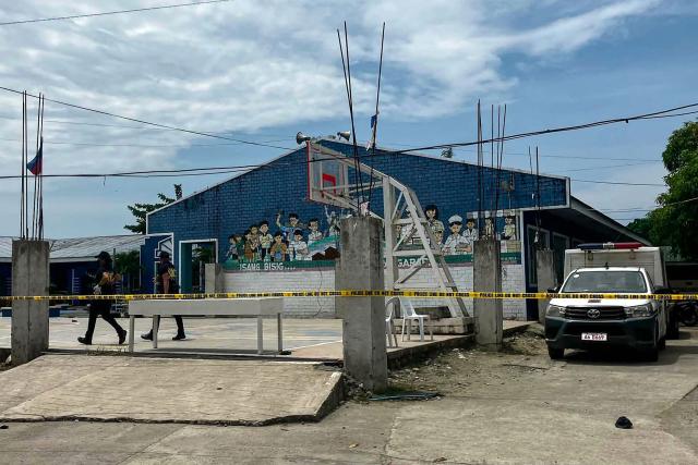 Police investigators walk in front of the school entrance after a shooting incident at a high school compound in Tacloban City, Leyte province on June 22, 2026. At least three teenaged students were killed and five others wounded on June 22, in a rare school shooting in the central Philippines, police said. (Photo by Noel  Sianosa / AFP)