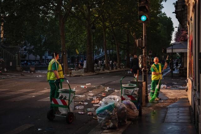 Municipal workers clean up food and drink waste on a street with the the Canal Saint-Martin in the background after the national annual street music festival 'Fete de la Musique' in Paris on June 22, 2026. (Photo by DIMITAR DILKOFF / AFP)