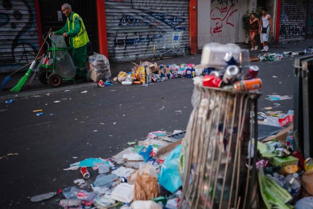 A municipal worker (L) cleans up food and drink waste on the morning following the national annual street music festival 'Fete de la Musique' in Paris on June 22, 2026. (Photo by DIMITAR DILKOFF / AFP)