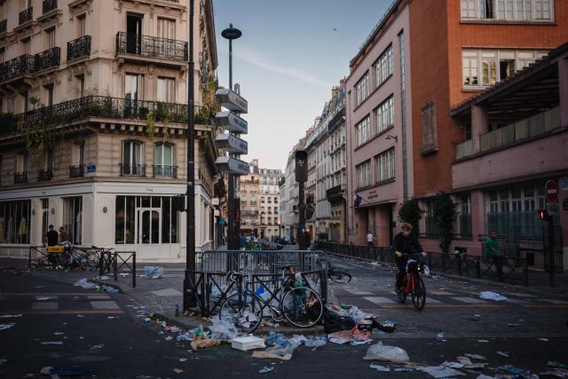 A cyclist rides past food and drink waste in a street on the morning following the national annual street music festival 'Fete de la Musique' in Paris on June 22, 2026. (Photo by DIMITAR DILKOFF / AFP)