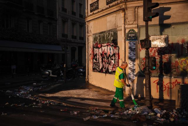 A municipal worker cleans up food and drink waste near the Canal Saint-Martin on the morning following the national annual street music festival 'Fete de la Musique' in Paris on June 22, 2026. (Photo by DIMITAR DILKOFF / AFP)