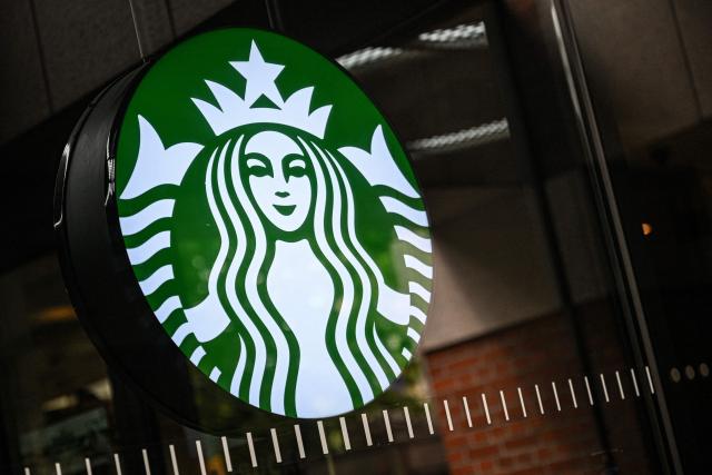 The logo of Starbucks coffee company is seen on a shop's window in Seoul on June 22, 2026. Lights off. Doors closed. This was the scene across more than 2,000 Starbucks shops in South Korea on Monday afternoon, as all staff underwent "historical and social awareness" learning sessions in the wake of the "Tank Day" fiasco. (Photo by Jade GAO / AFP)