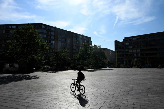 A man rides his bike across the Place Flagey square in Brussels during a heatwave on June 22, 2026. Much of Europe is preparing on June 22 for an already fierce heatwave to intensify even further in the coming days, with some countries taking special measures to mitigate its effects. A leading researcher reiterated that human-driven climate change had contributed to the recent record-breaking heatwave. (Photo by Nicolas TUCAT / AFP)