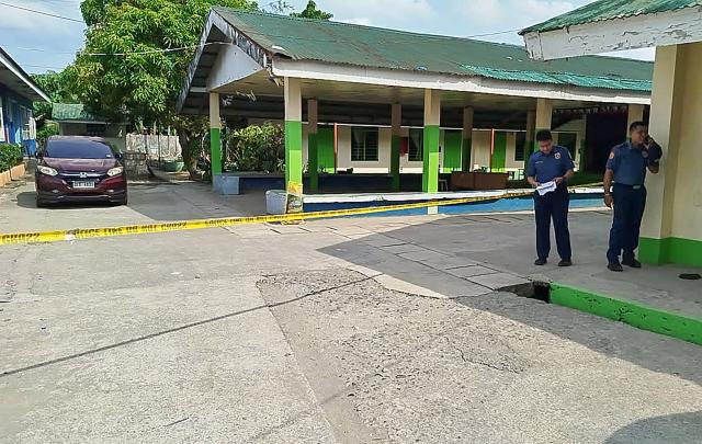 Policemen stand near the crime scene of a school compound after a shooting incident at a high school compound in Tacloban City, Leyte province on June 22, 2026. At least three teenaged students were killed and five others wounded on June 22, in a rare school shooting in the central Philippines, police said. (Photo by Noel  Sianosa / AFP)