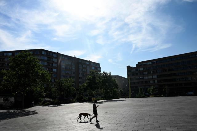 A man walks his dog across the Place Flagey square in Brussels during a heatwave on June 22, 2026. Much of Europe is preparing on June 22 for an already fierce heatwave to intensify even further in the coming days, with some countries taking special measures to mitigate its effects. A leading researcher reiterated that human-driven climate change had contributed to the recent record-breaking heatwave. (Photo by Nicolas TUCAT / AFP)