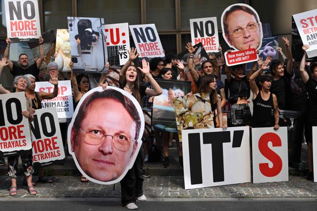 Activists hold placard reading "No more betrayals" and portraits of EU Commissioner for Health and animal Welfare Oliver Varhelyi as they demonstrate to ask more equality and better transport conditions for farm animals, next to the EU institutions, in Brussels on June 22, 2026. (Photo by Nicolas TUCAT / AFP)