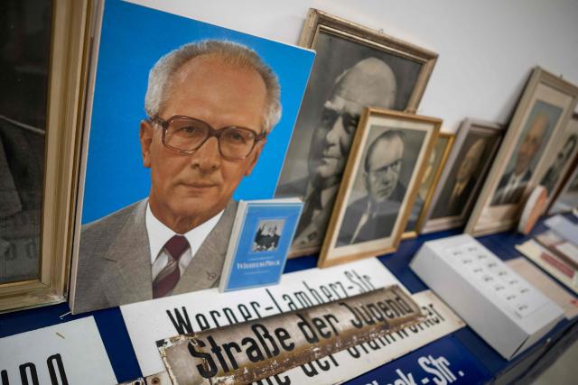 A portrait of former East German leader Erich Honecker (L) along with former East German street signs are on display at the DDR Museum Depot in Berlin on June 17, 2026. The museum collects and preserves cultural assets of the former Communist German Democratic Republic (GDR) having assembled over 400,000 different objects in their collection. (Photo by John MACDOUGALL / AFP)