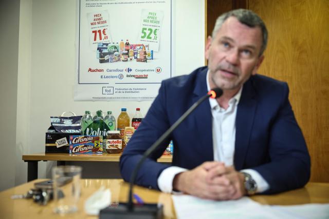 Chairman of Les Mousquetaires retail group Thierry Cotillard speaks during a press conference as a collection of twelve consumers goods is seen behind him at the Federation du Commerce et de la Distribution (FCD) in Paris on June 22, 2026. Five major retail groups presented to the press on June 22, 2026, a basket of twelve products whose price had been negotiated with manufacturers, in order to demonstrate the decisive role of commercial negotiation for purchasing power. (Photo by Simon WOHLFAHRT / AFP)