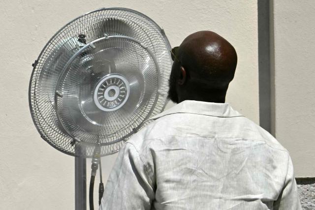 A guest stands in front of a fan to cool down before the Thom Browne collection show at Milan's Fashion Week Menswear Spring/Summer 2027, in Milan on June 22, 2026. (Photo by Stefano RELLANDINI / AFP)