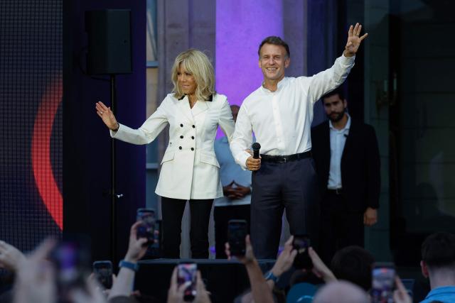 France's President Emmanuel Macron (R), acccompanied by his wife Brigitte Macron waves to attendees during the annual street music festival 'Fete de la Musique' and amid a heat wave at the Presidential Elysee Palace in Paris on June 21, 2026. (Photo by Yoan VALAT / POOL / AFP)