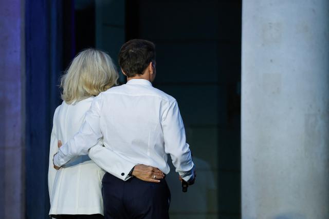 France's President Emmanuel Macron (R), acccompanied by his wife Brigitte Macron leave the stage after delivering a speech during the annual street music festival 'Fete de la Musique' and amid a heat wave at the Presidential Elysee Palace in Paris on June 21, 2026. (Photo by Yoan VALAT / POOL / AFP)