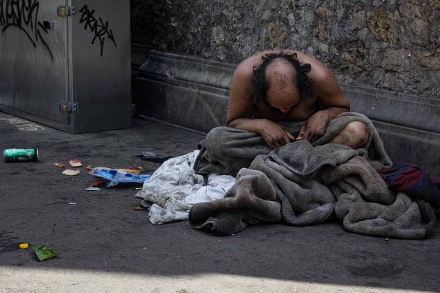 A homelesss person sits on the pavement with the heatwave set to intensify across much of Europe, forcing warnings and special measures, in Paris on June 20, 2026. (Photo by JOEL SAGET / AFP)