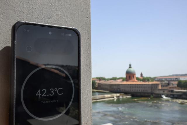 A thermometer-enabled telephone shows the temperature of a support beam on a building overlooking the Garonne river in Toulouse during a heatwave on June 22, 2026. (Photo by Ed JONES / AFP)