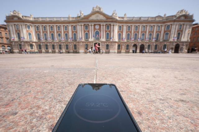 A thermometer-enabled telephone shows the temperature of the stone surface of the central Capitol square in on a street in Toulouse during a heatwave on June 22, 2026. (Photo by Ed JONES / AFP)