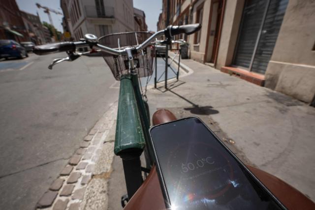 A thermometer-enabled telephone shows the temperature of a bicycle seat on a street in Toulouse during a heatwave on June 22, 2026. (Photo by Ed JONES / AFP)