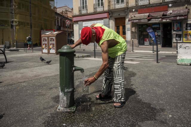 A man fills a cup from a water fountain in Toulouse during a heatwave on June 22, 2026. (Photo by Ed JONES / AFP)