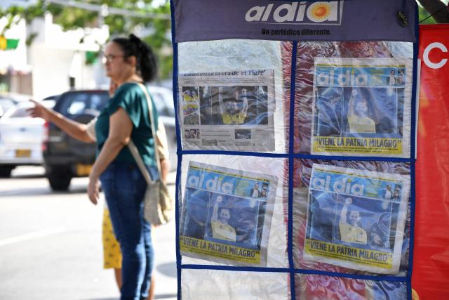A woman stands next to front pages of newspapers displayed at a newsstand in Barranquilla, Colombia, on June 22, 2026, the day after the presidential election runoff. The streets of the Colombian city of Barranquilla turned into a carnival on the night of June 21, 2026, after hard-right Abelardo de la Espriella beat his leftist rival to win the country's presidential runoff election. (Photo by Jaime SALDARRIAGA / AFP)