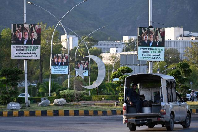 A commuter rides past electronic boards featuring Iran's President Masoud Pezeshkian (C), Pakistan's Prime Minister Shehbaz Sharif (L) and President Asif Ali Zardari, displayed along a street in Islamabad on June 22, 2026 on the eve of Pezeshkian's visit to Pakistan amid the US-Iran peace talks. Iranian President Masoud Pezeshkian will travel to Pakistan on June 23, state media reported, following talks between Tehran and Washington in Switzerland which were mediated by Islamabad. (Photo by Aamir QURESHI / AFP)
