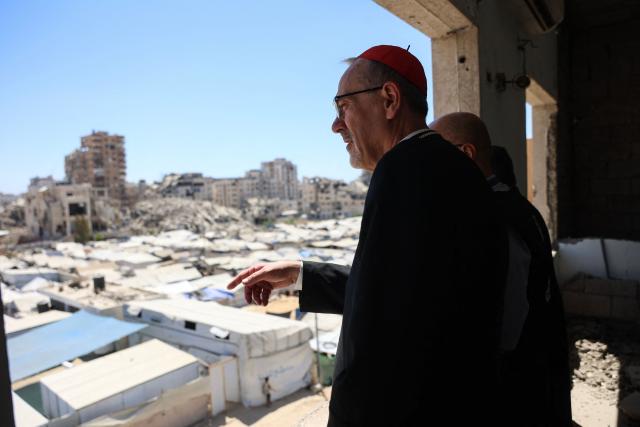 Jerusalem's Latin Patriarch Cardinal Pierbattista Pizzaballa stands on a building overlooking makeshift shelters for displaced Palestinians during a visit to the Tel al-Hawa neighbourhood of Gaza City on June 22, 2026. Pizzaballa pledged on June 22 not to abandon Gaza's Christian community as he visited the territory with his Greek Orthodox counterpart. Pizzaballa and Patriarch Theophilos III arrived for a pastoral visit aimed at supporting both Gaza's small Christian population and its wider community after years of war and hardship. (Photo by Omar AL-QATTAA / AFP)