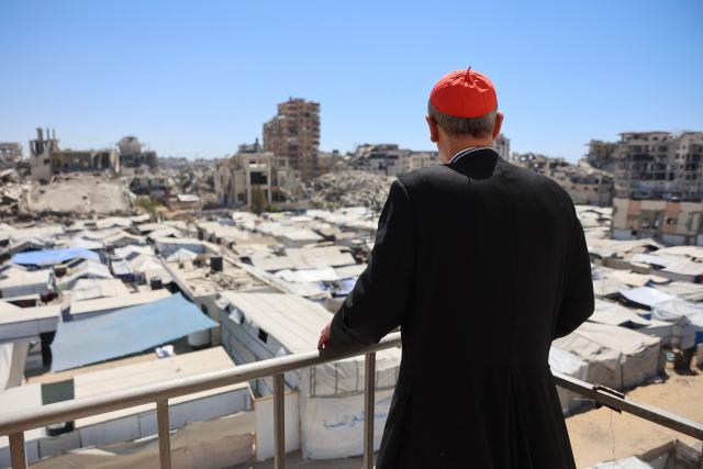 Jerusalem's Latin Patriarch Cardinal Pierbattista Pizzaballa stands on a building overlooking makeshift shelters for displaced Palestinians during a visit to the Tel al-Hawa neighbourhood of Gaza City on June 22, 2026. Pizzaballa pledged on June 22 not to abandon Gaza's Christian community as he visited the territory with his Greek Orthodox counterpart. Pizzaballa and Patriarch Theophilos III arrived for a pastoral visit aimed at supporting both Gaza's small Christian population and its wider community after years of war and hardship. (Photo by Omar AL-QATTAA / AFP)
