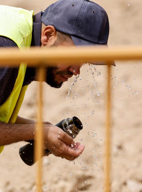 A worker cools off with water at a road construction site in Madrid on June 22, 2026, during the heat wave affecting the Iberian Peninsula. National weather agency AEMET issued an orange heat warning – the second-highest level - for the Madrid region, with temperatures forecast to reach 40C. Large parts of Spain experience unusually high temperatures for June as a mass of hot air from North Africa moves across the Iberian Peninsula. (Photo by OSCAR DEL POZO / AFP)