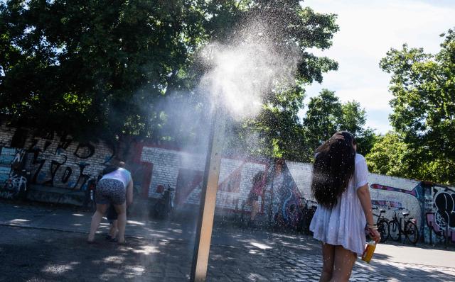 A woman cools off at a mist spraying fountain, known as a "cooling point", in Berlin on June 22, 2026. (Photo by John MACDOUGALL / AFP)