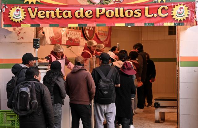 People wait in line to buy chicken at a commercial establishment in downtown La Paz, Bolivia, on June 22, 2026. Bolivian police driving bulldozers cleared highways on June 21, 2026 and fuel trucks rolled into La Paz after the president declared a state of emergency to remove anti-government roadblocks that had paralyzed the Andean nation. (Photo by MARTIN BERNETTI / AFP)