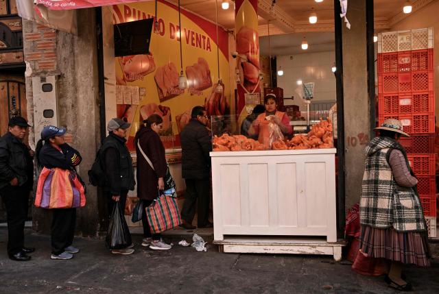 People wait in line to buy chicken at a commercial establishment in downtown La Paz, Bolivia, on June 22, 2026. Bolivian police driving bulldozers cleared highways on June 21, 2026 and fuel trucks rolled into La Paz after the president declared a state of emergency to remove anti-government roadblocks that had paralyzed the Andean nation. (Photo by MARTIN BERNETTI / AFP)