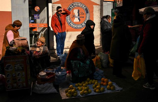 Indigenous people sell agricultural products on a street in downtown La Paz, Bolivia, on June 22, 2026. Bolivian police driving bulldozers cleared highways on June 21, 2026 and fuel trucks rolled into La Paz after the president declared a state of emergency to remove anti-government roadblocks that had paralyzed the Andean nation. (Photo by MARTIN BERNETTI / AFP)