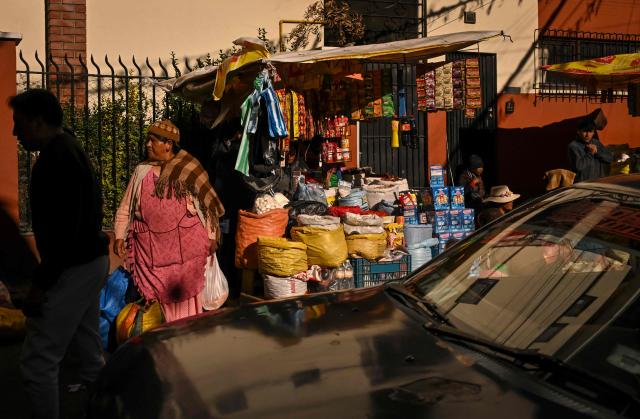 An Indigenous woman sells agricultural products on a street in downtown La Paz, Bolivia, on June 22, 2026. Bolivian police driving bulldozers cleared highways on June 21, 2026 and fuel trucks rolled into La Paz after the president declared a state of emergency to remove anti-government roadblocks that had paralyzed the Andean nation. (Photo by MARTIN BERNETTI / AFP)