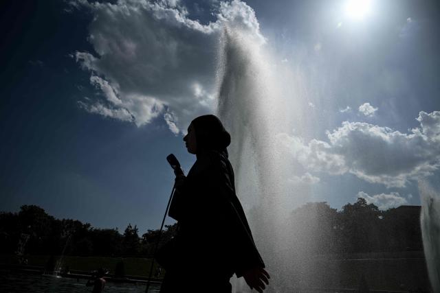 A pedestrian holding a fan walks by the Trocadero Fountain during a heatwave in Paris on June 22, 2026. The latest bout of exceptionally high temperatures to hit Europe has seen outdoor events cancelled, transport disrupted, schools shut and office workers told to work from home, as the authorities issued health alerts to protect the elderly and vulnerable. In France, the epicentre of the weather anomaly, 54 of the country's 96 mainland departments were on the highest heat alert, with temperatures forecast to climb up to 43C in the southwestern city of Bordeaux and 39C in the capital Paris, said national weather service Meteo-France. (Photo by JULIEN DE ROSA / AFP)