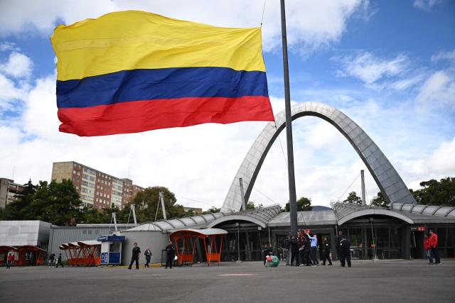 Employees hoist a Colombian national flag outside Corferias, the largest polling center in the country, during the vote count, the day after the presidential election runoff, in Bogota on June 22, 2026. Rightist leaders from across the Americas congratulated Colombia's hard-right president-elect Abelardo de la Espriella after he defeated his leftist rival in a razor-tight vote on June 21, 2026. With almost all the votes counted, De la Espriella held 49.66 percent of the ballots versus Senator Ivan Cepeda's 48.70 percent. (Photo by Raul ARBOLEDA / AFP)