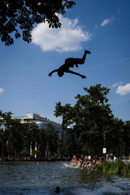 Young people jump from a bridge into the Canal Saint-Martin during a heatwave in Paris on June 22, 2026. Due to the ongoing heatwave sweeping across France - the Bassin des Recollets - a portion of the Canal Saint-Martin in the French capital has been opened for swimming from June 17. (Photo by JOEL SAGET / AFP)