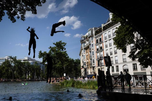 Young people jump from a bridge into the Canal Saint-Martin during a heatwave in Paris on June 22, 2026. Due to the ongoing heatwave sweeping across France - the Bassin des Recollets - a portion of the Canal Saint-Martin in the French capital has been opened for swimming from June 17. (Photo by JOEL SAGET / AFP)